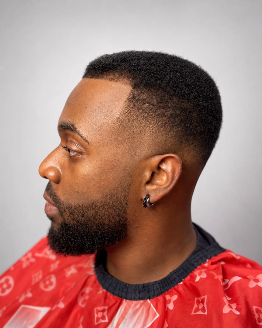 Rounded afro with a sharp line-up, drop fade, and a full beard.